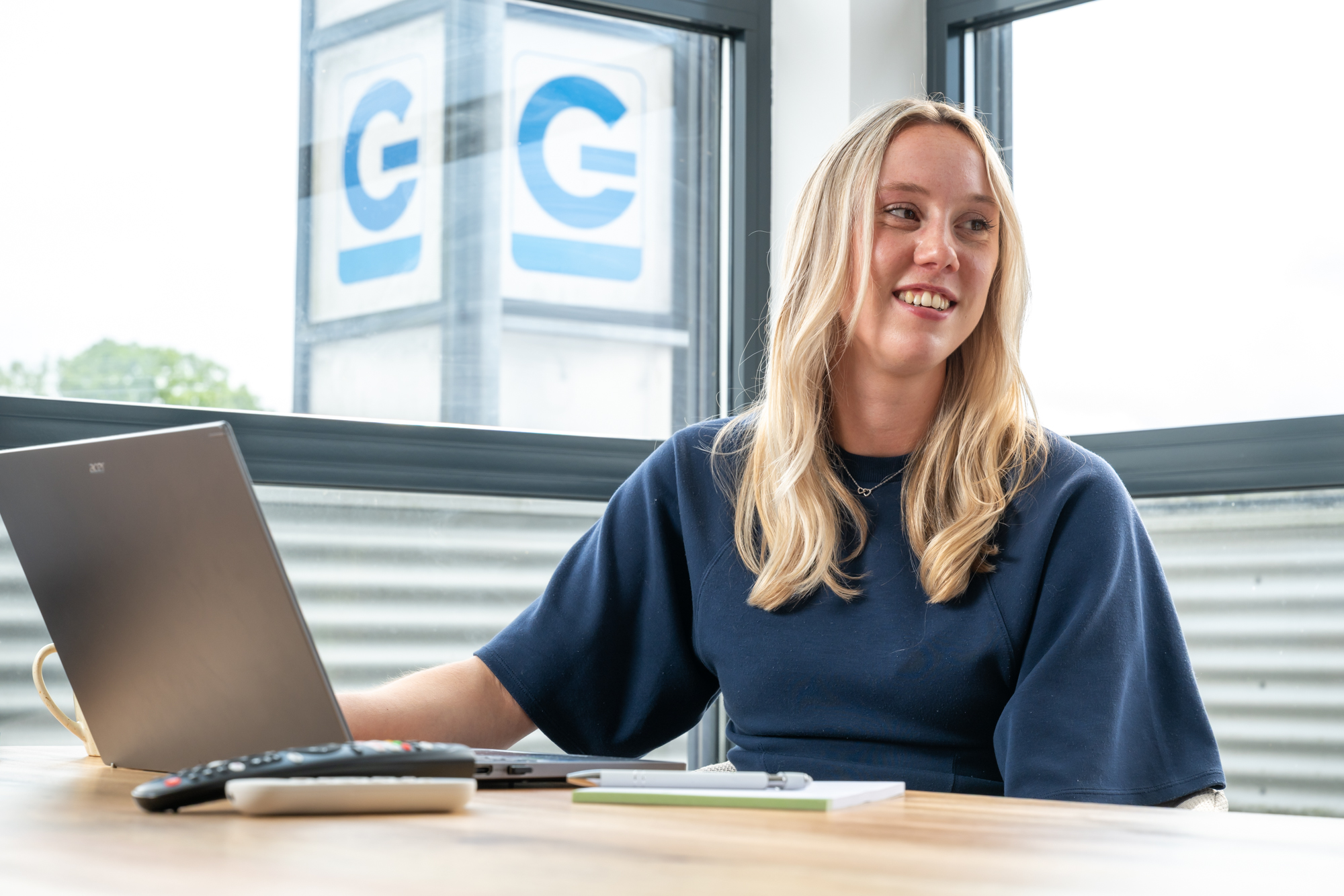 Sanne lacht tijdens een overleg achter haar laptop